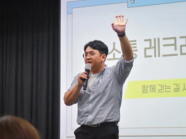 소통 레크리에이션 화면 앞에서 손을 들고 진행하는 강진우 대표