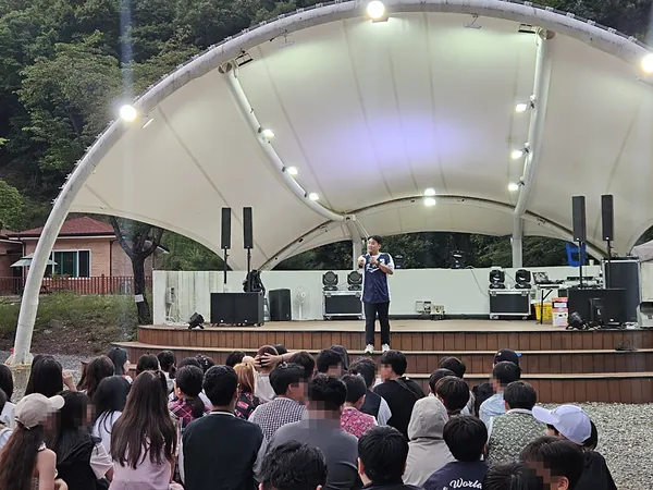 야외 공연장 무대에서 학생들 앞에 선 강진우 대표