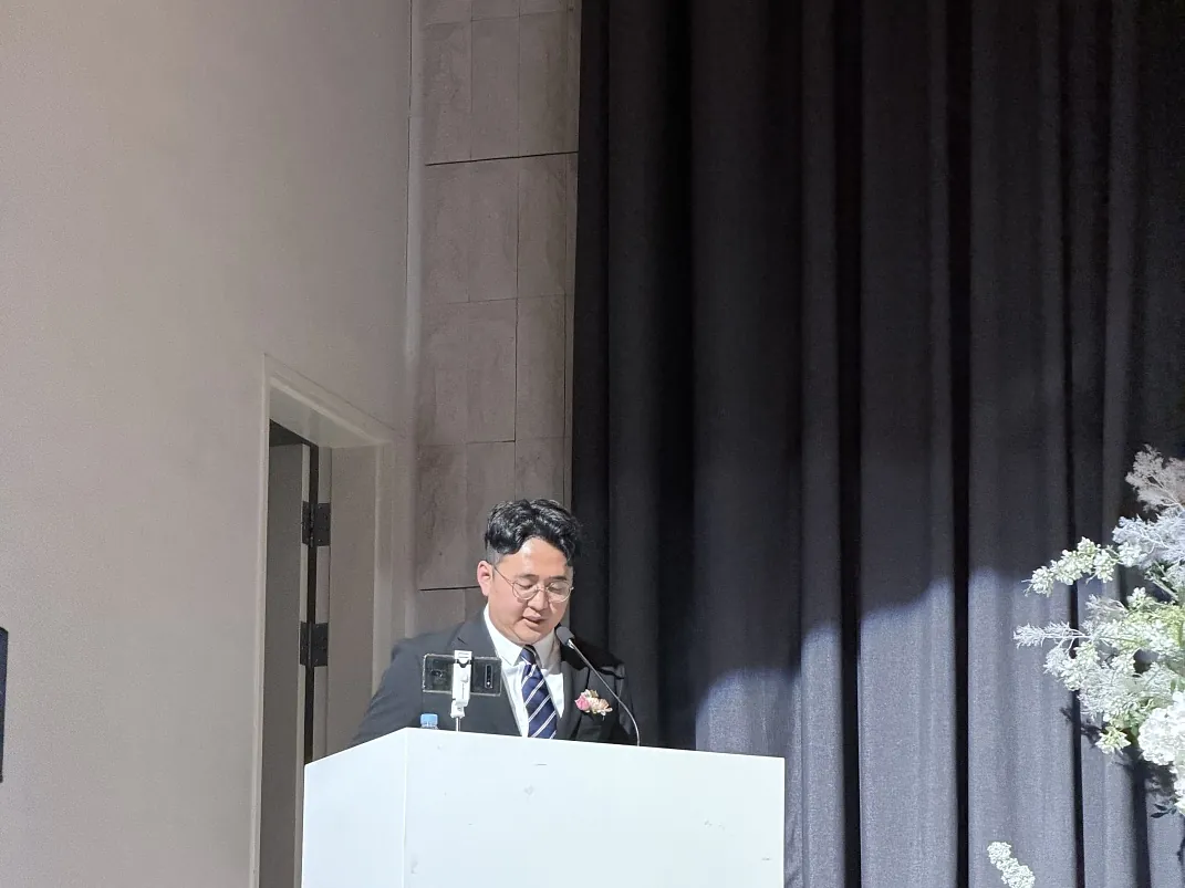 꽃장식이 놓인 결혼식장 단상에서 사회를 보는 강진우 대표
